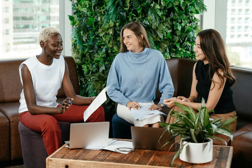 How to Choose the Right Plant for Office Space: A Comprehensive Guide 6 Diverse glad colleagues with papers speaking together at table with netbooks in conference hall with verdant plants