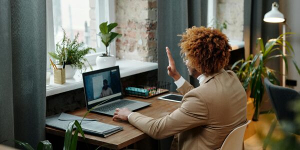 Business professional waving during a video call in a stylish modern office setting.