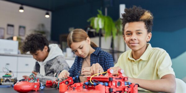 Three kids collaborating on a robotics project in a modern classroom setting.
